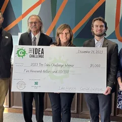 UWEC Entrepreneurship graduate Jackson Anderson holding a check that will help fund his swimming lesson and hydrotherapy startup.